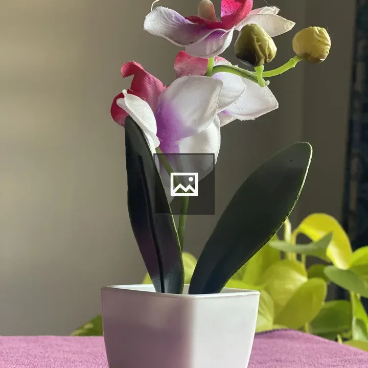 Artificial orchid in small white pot