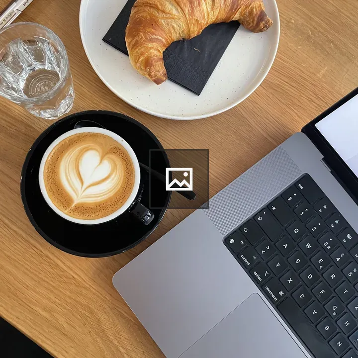 Croissant, coffee and laptop on table