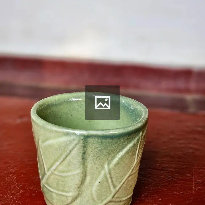 Green ceramic cup with leaf patterns