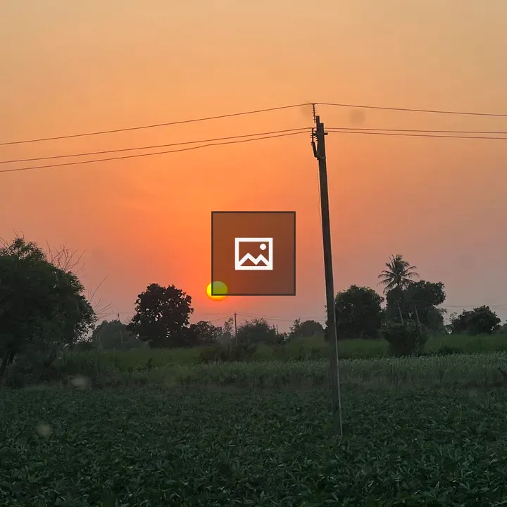 Sunset over green fields with a pole