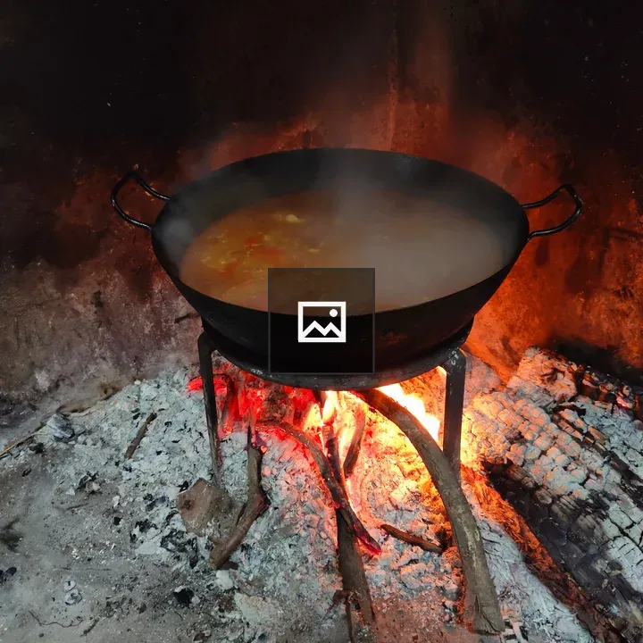 Pan with liquid and ingredients over embers