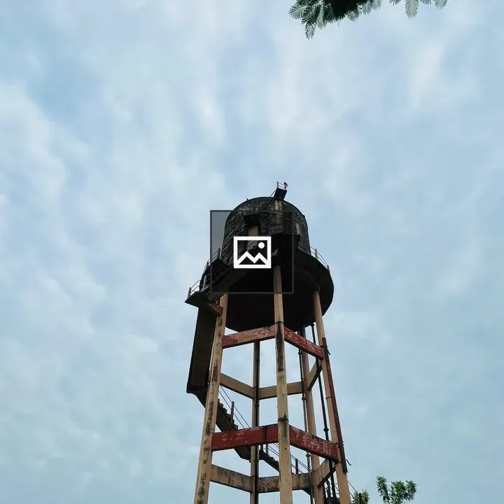 Weathered water tank against cloudy sky
