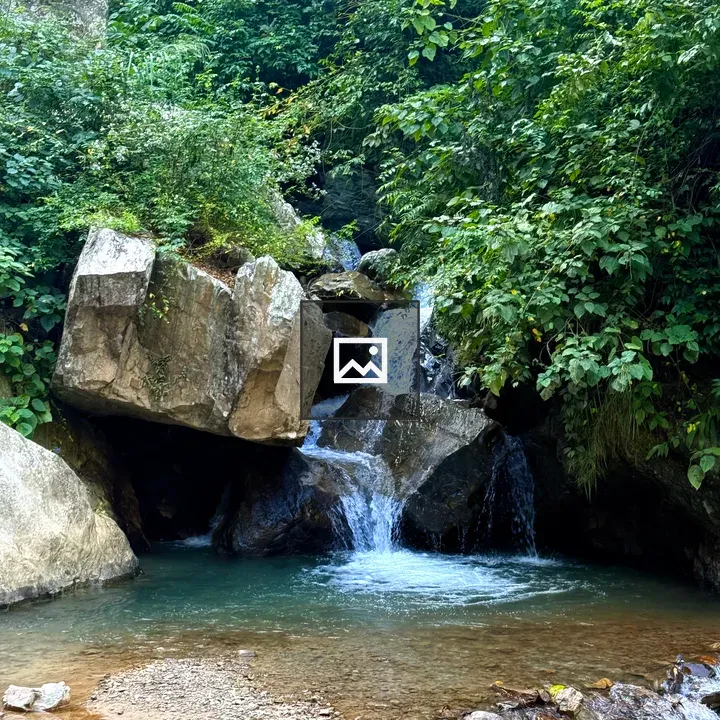 Waterfall over rocks into turquoise pond