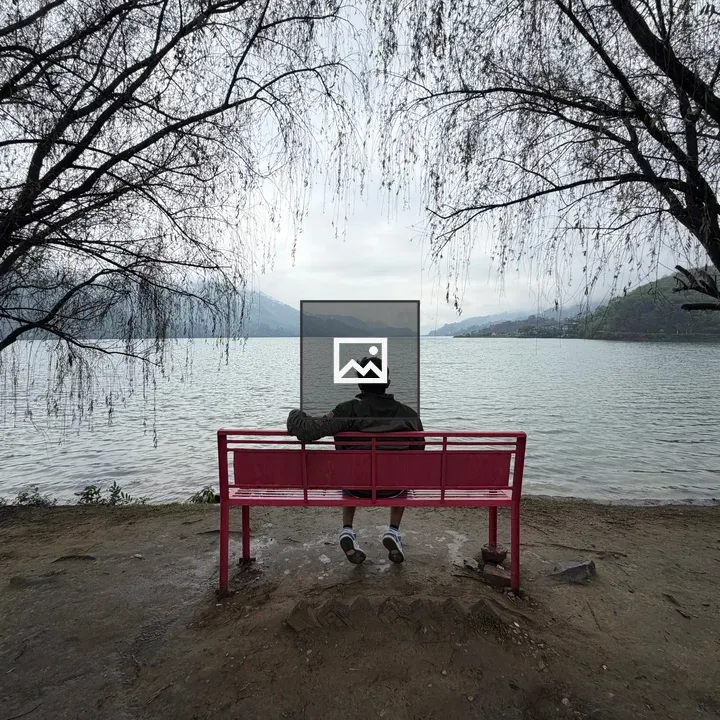 Person on red bench by calm lake