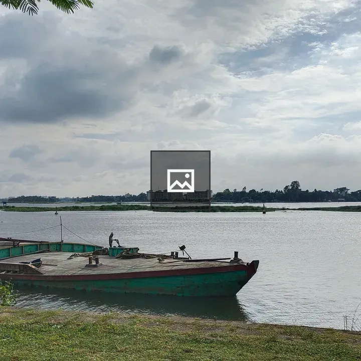 Boat by riverbank under cloudy sky