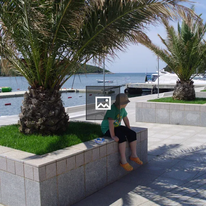 Kid on Concrete Bench by Palm