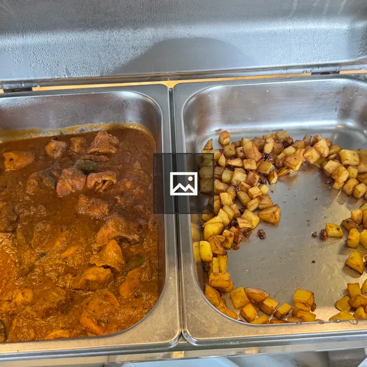 Two buffet trays of beef curry and roasted potatoes