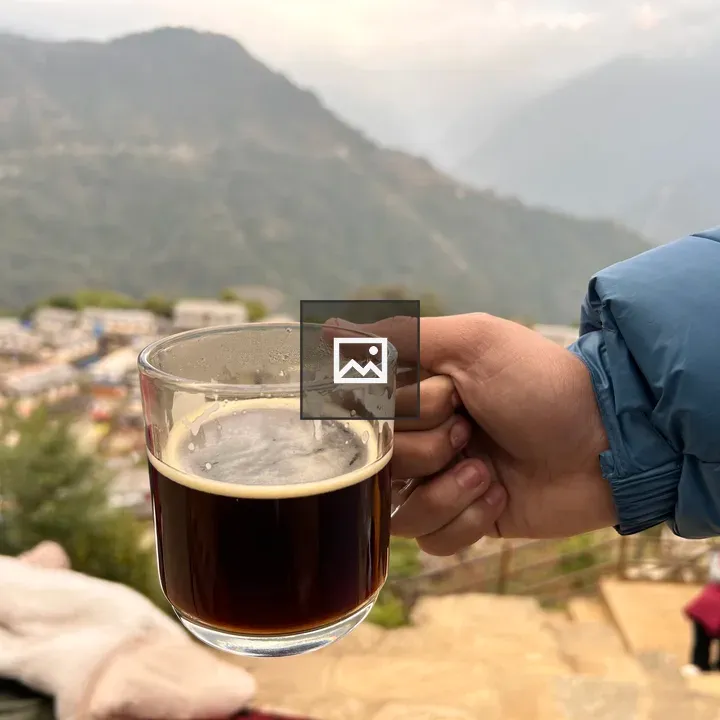 Coffee Cup in Hand with Village Background