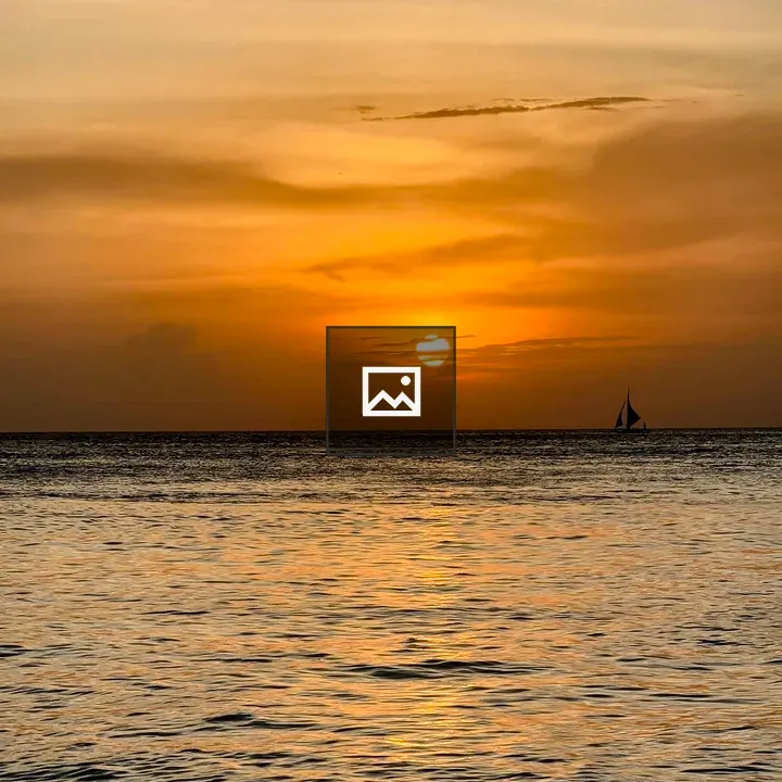 Silhouetted sailboat at sunset horizon