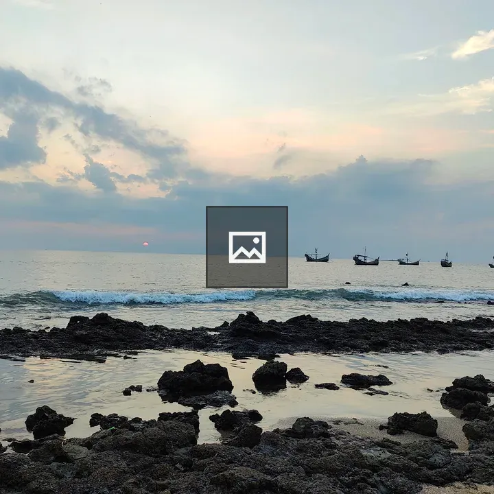 Sunset from rocky beach with boats
