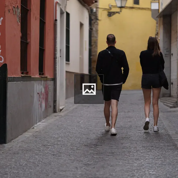 Two People Walking on Cobblestone Street