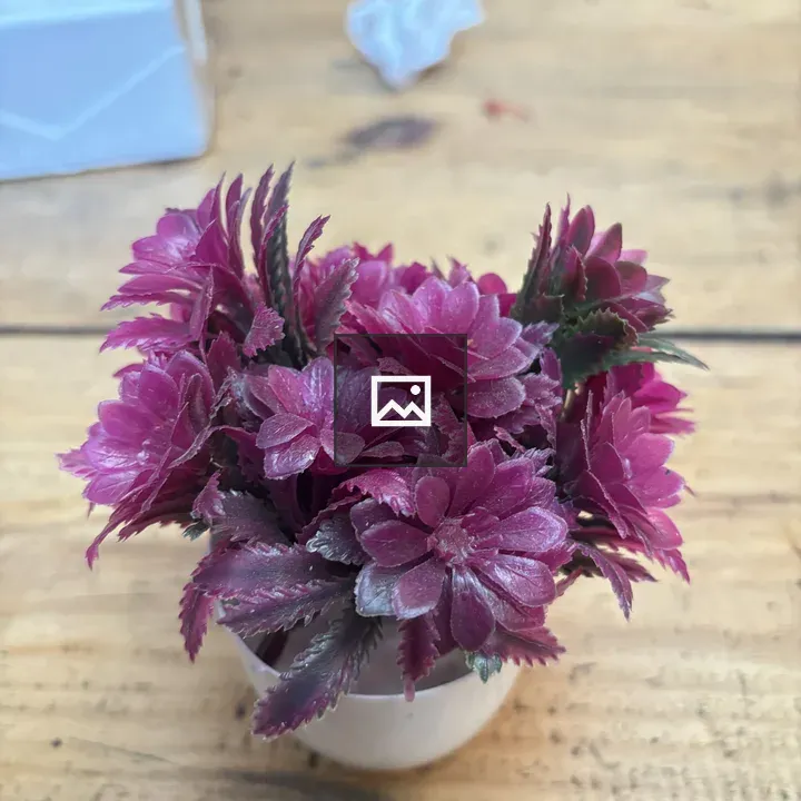 Pink artificial flowers in a white pot