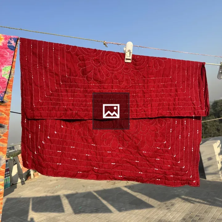 Red hand-stitched quilt on clothesline