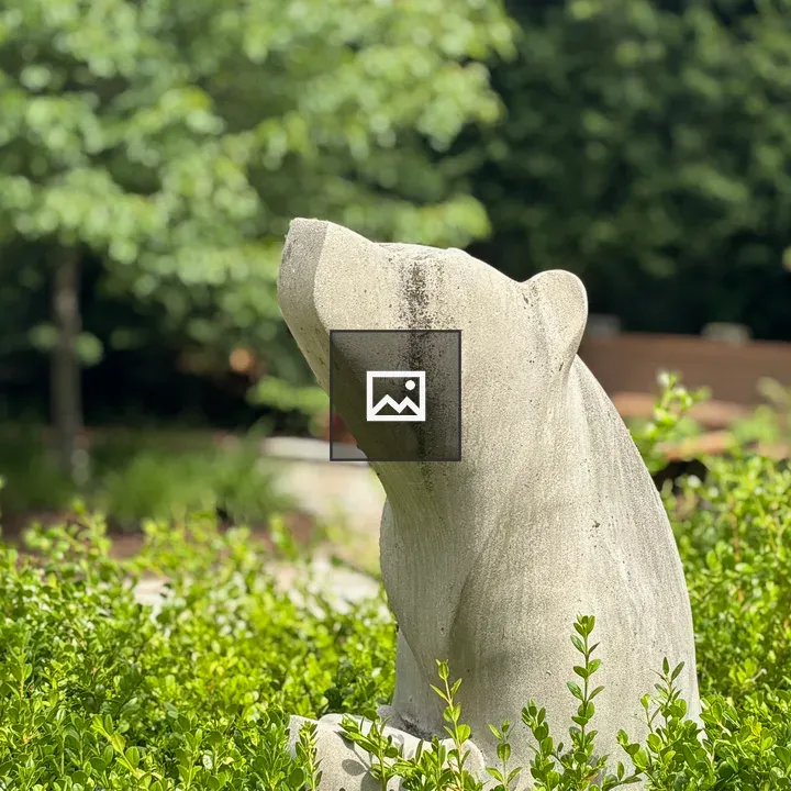 Concrete bear sculpture in bushes
