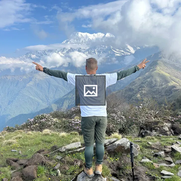 Person on grassy hilltop with mountains