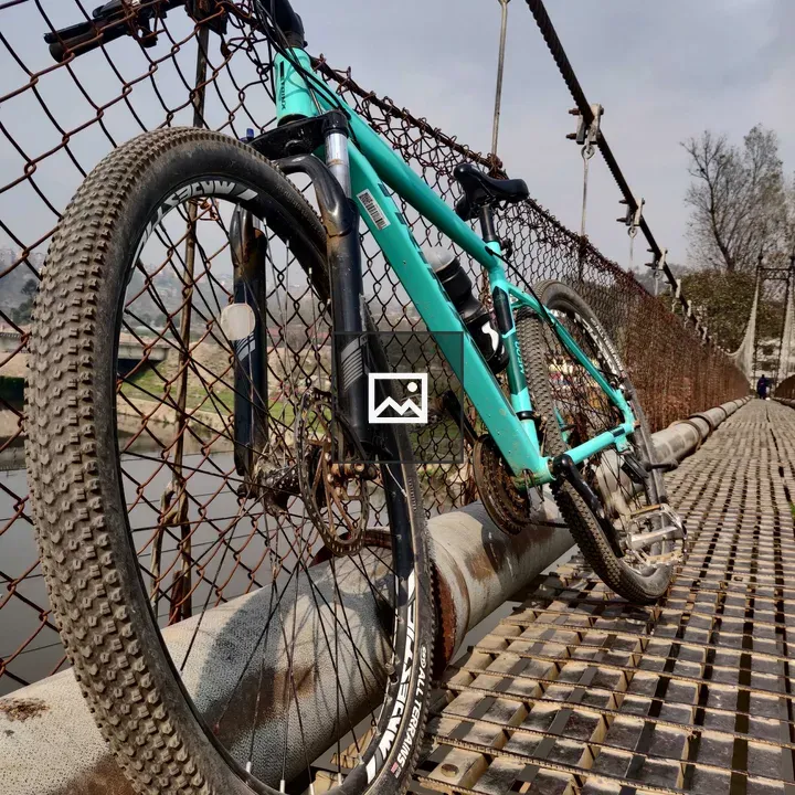 Green bicycle on bridge fence