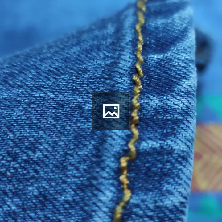 Hem of blue jeans with golden thread