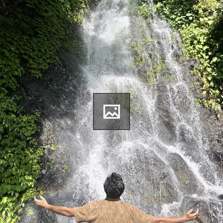 Person by waterfall with outstretched arms