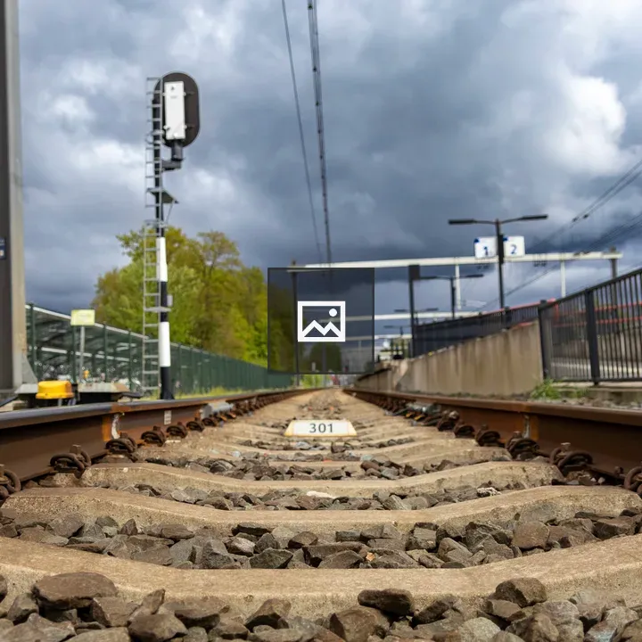 Train tracks and signal under stormy skies