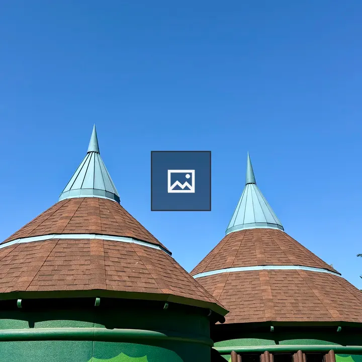 Two round green buildings with cone roofs