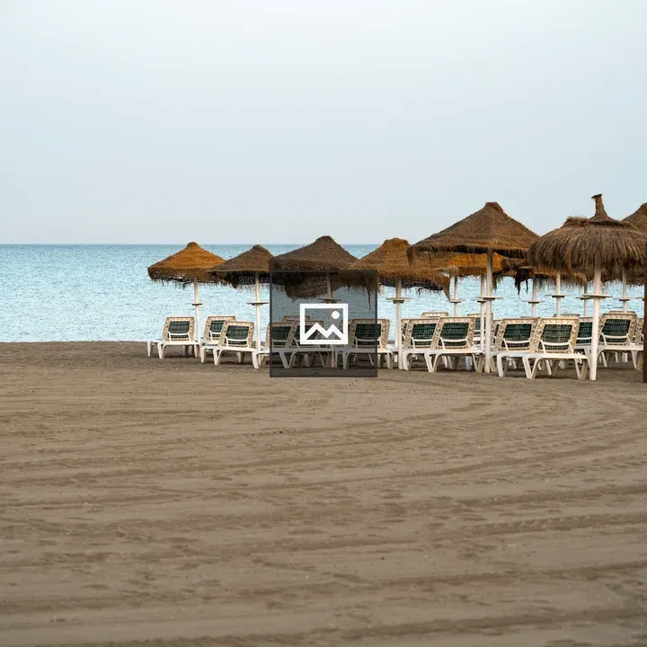 Beach lounge chairs under straw umbrellas