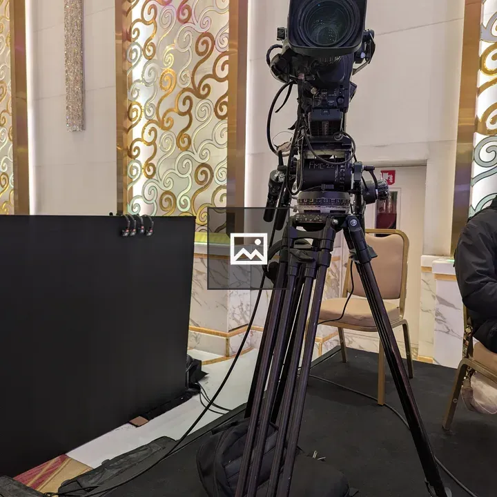 Video camera on tripod on black stage
