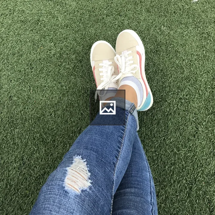 Crossed legs in ripped jeans and sneakers