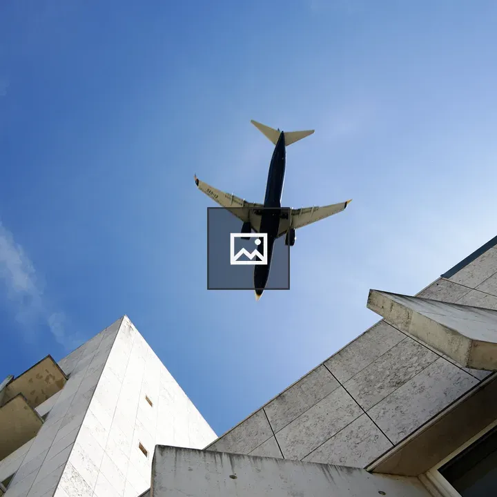 Airplane over Blue Sky and Building