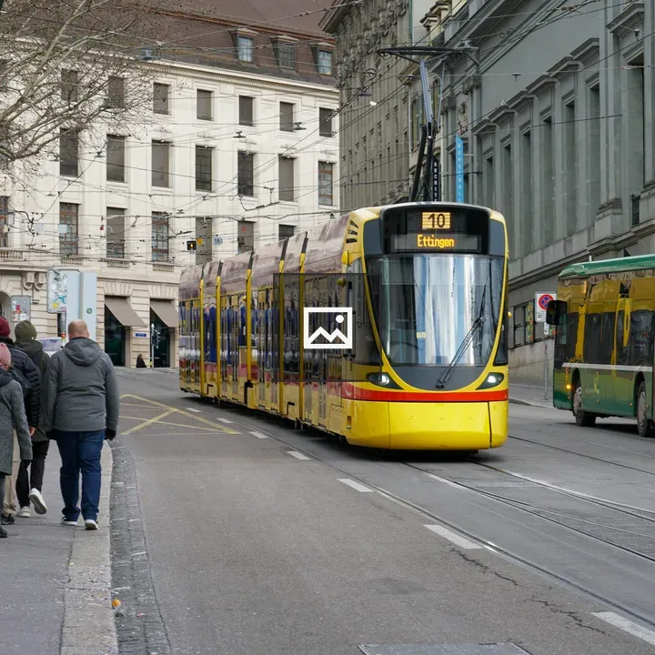 Yellow tram with green bus in city street