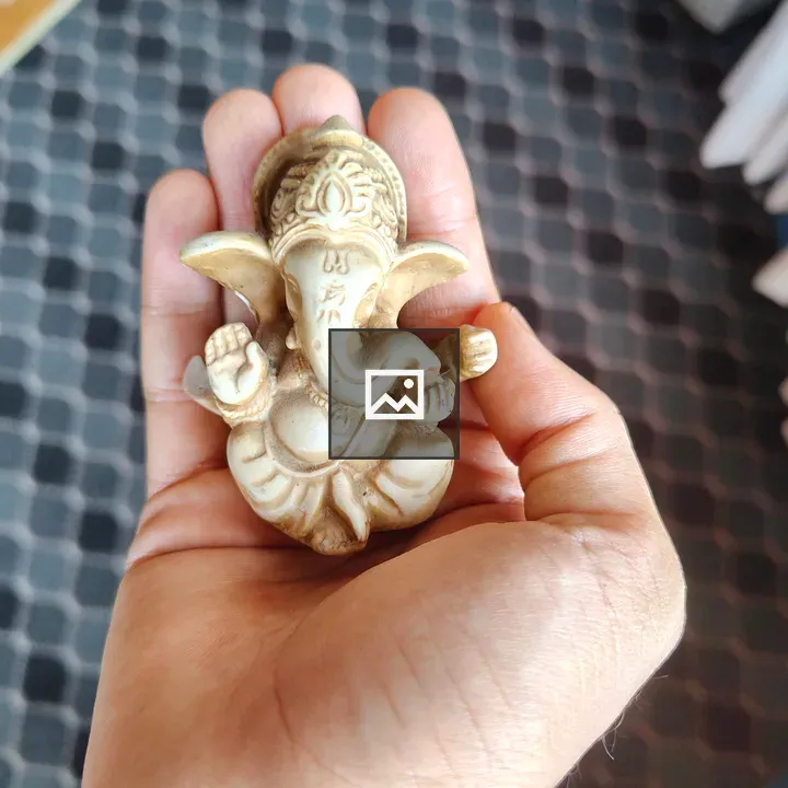 Hand holding carved Lord Ganesha statue
