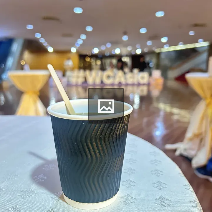 Black disposable coffee cup on patterned tablecloth