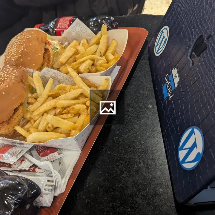 Two burgers with fries and a drink