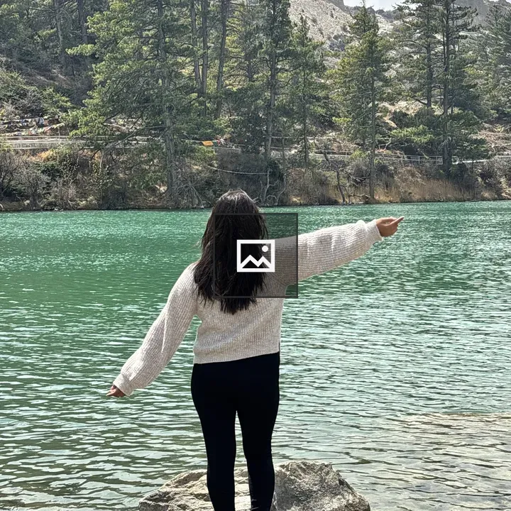 Woman on rock by turquoise lake