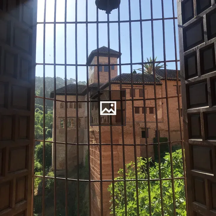 A barred window view of Alhambra buildings