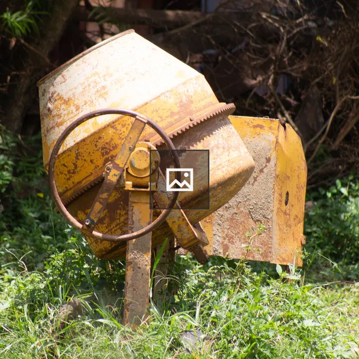 Yellow concrete mixer in grass