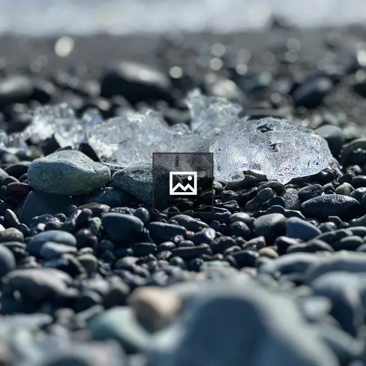 Ice remains on black pebble beach
