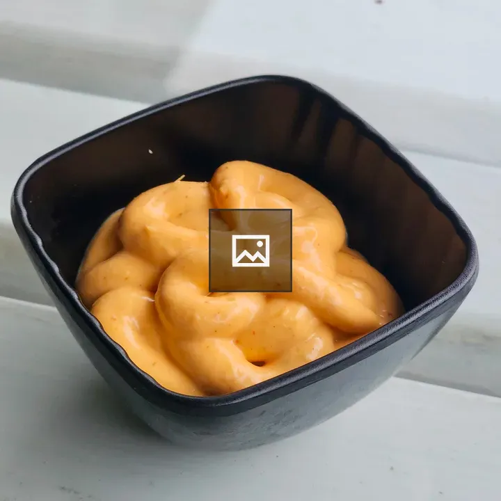 Creamy orange mayo in a black bowl
