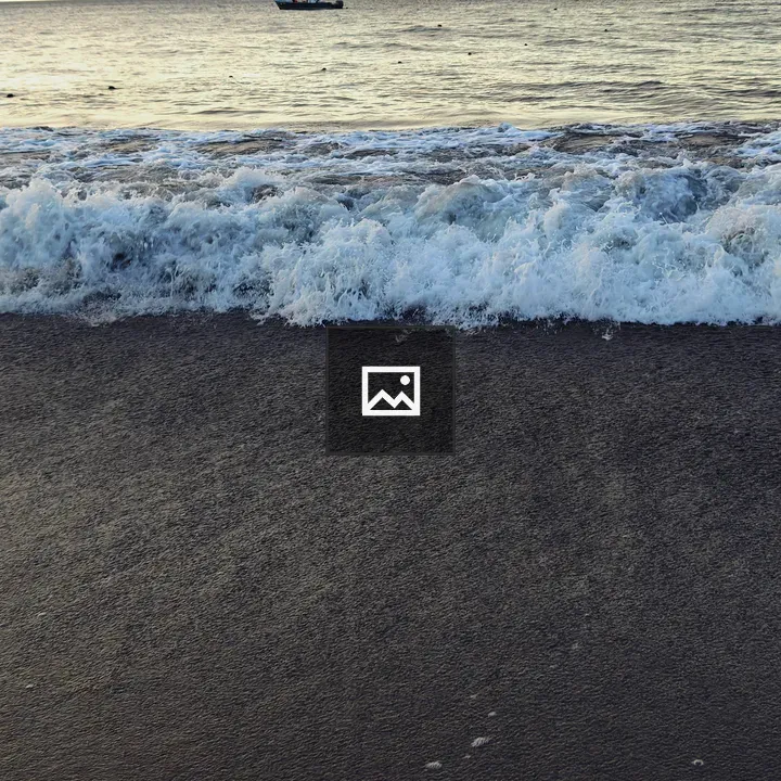 Dark sand and white waves on shore