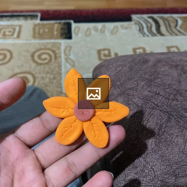 Orange clay flower in hand