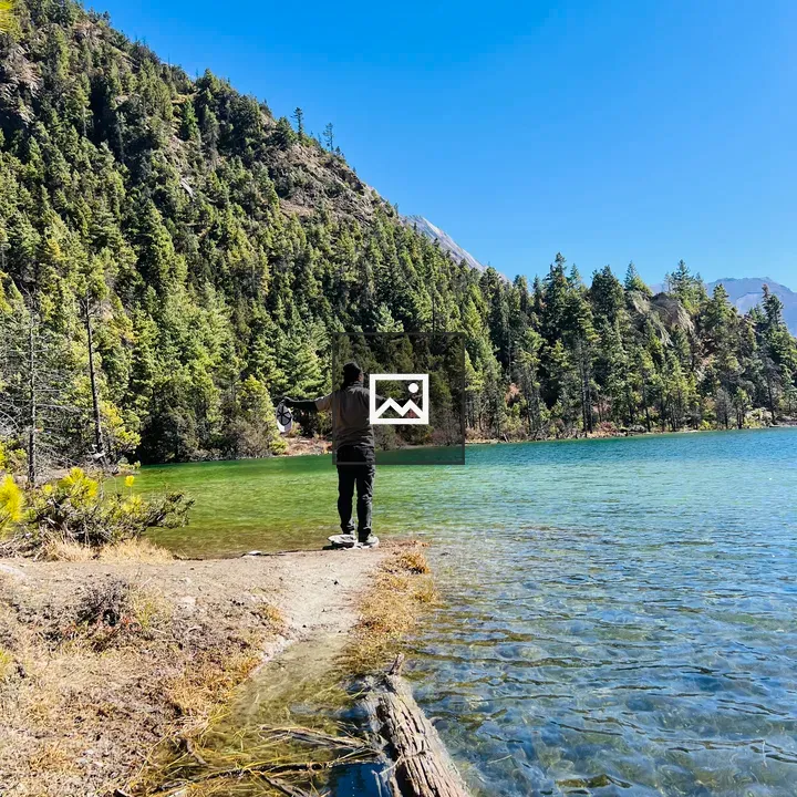 Person at lake edge with arms outstretched