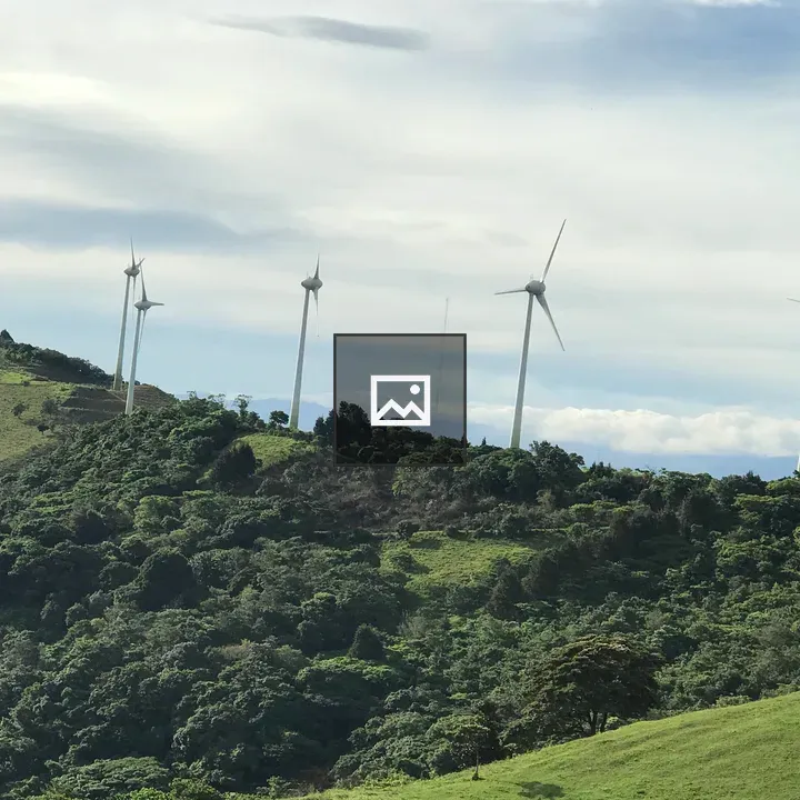 Wind turbines above green hills