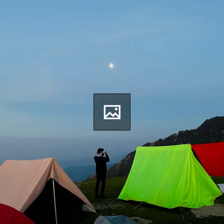 Man beside colourful tents on mountain