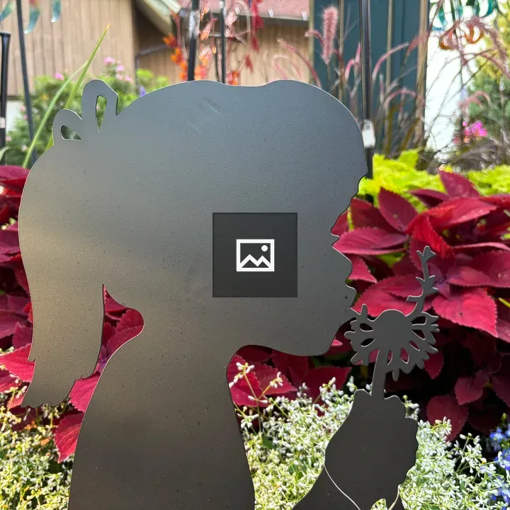 Steel silhouette of a child blowing on a dandelion