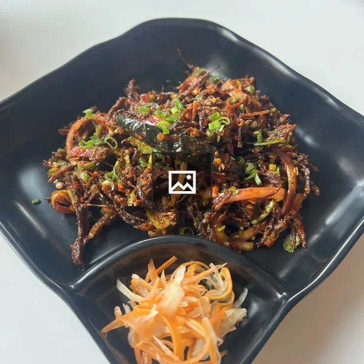 Shredded meat dish on black plate