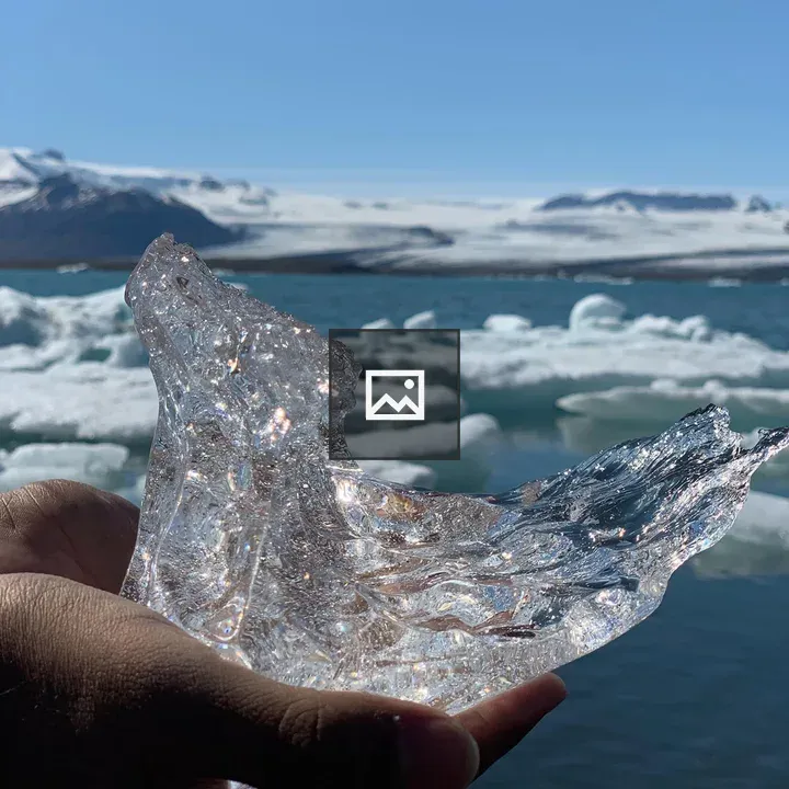 Hand Holding Ice on River Bank