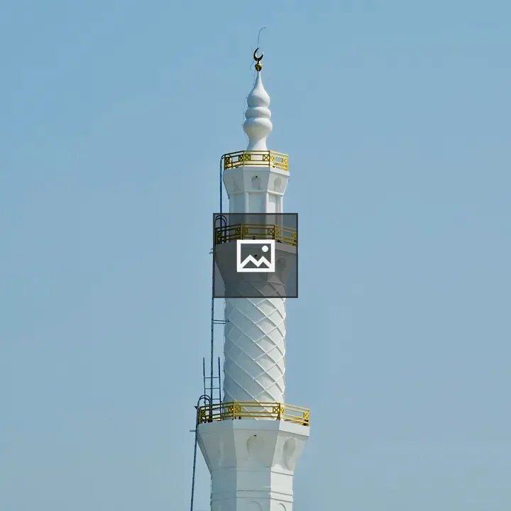 Tall mosque minaret against blue sky