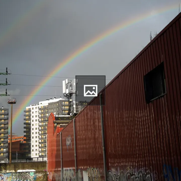Rainbow over cityscape with graffiti wall