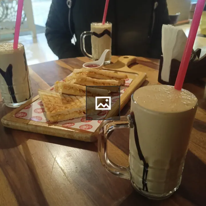 Three milkshakes and sandwiches on table
