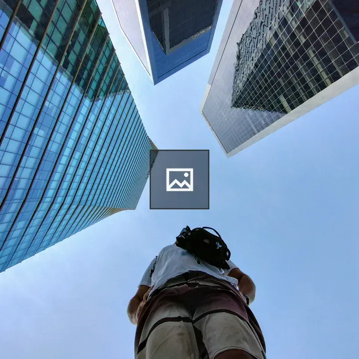 Person with backpack among tall glass skyscrapers