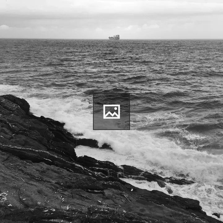Ship at sea with rocks foreground